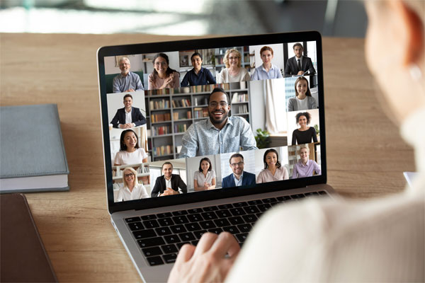 Image of a man on a laptop with a video conference on screen
