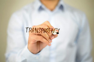 Image of a person drawing the word Transparency on a transparent board