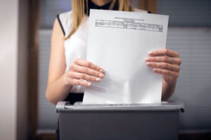 Woman putting a legal document through a shredding machine